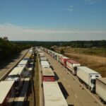 Aerial view of heavy traffic with trucks on an English highway under blue skies.