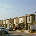 A view of modern suburban houses with parked cars on a sunny day in Monterrey, Mexico.