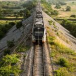 Aerial view of a train on railway tracks crossing the rural countryside of Montenegro in summer.