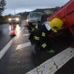 Firefighter attending to an overturned car on a rainy road in Póvoa de Lanhoso, Braga, Portugal.