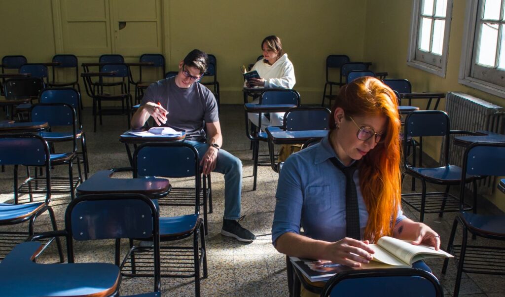 Three students studying in a sunlit classroom in Buenos Aires, Argentina.