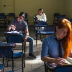 Three students studying in a sunlit classroom in Buenos Aires, Argentina.