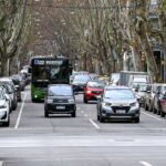 Traffic on a tree-lined street in Montevideo, Uruguay, featuring a public bus and cars.