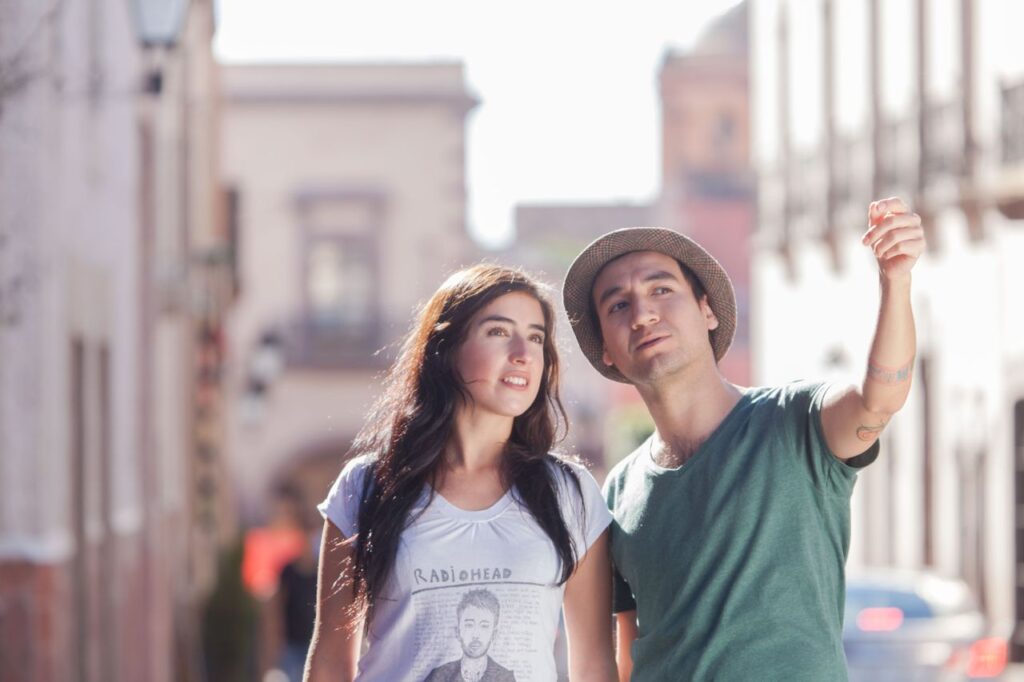 A young couple in casual wear exploring a vibrant urban street, enjoying a sunny day.