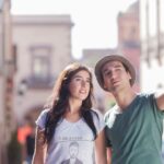 A young couple in casual wear exploring a vibrant urban street, enjoying a sunny day.